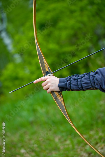 professional archer shooting with modern longbow in forest