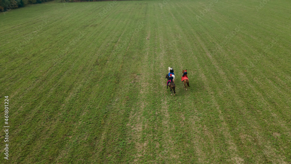Aerial view of group of fox hunters on the horses in the autumn field. Equestrian riding sport in a countryside. Aerial view of group of fox hunters on the horses in the autumn field. Equestrian riding sport in a countryside.