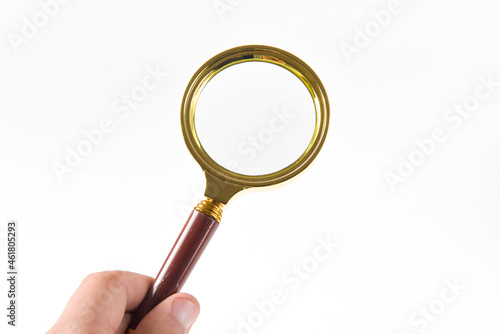 hand holding brass magnifying glass isolated on white background
