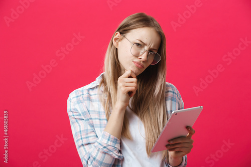 young business woman holding tablet and thinks on pink backgrouond photo