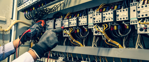 Electricity and electrical maintenance service, Close-up circuit breaker has engineer using measuring equipment checking electric volt at terminal block and cable wiring main power distribution board. photo