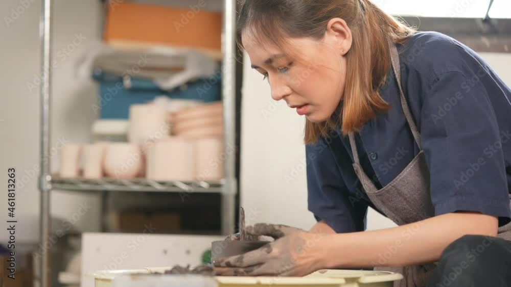4K Asian woman sculptor artist hands sculpture clay on pottery wheel at ceramic studio. Female craftsman molding raw clay create pottery shapes at workshop. Small business handicraft product concept. 4K Asian woman sculptor artist hands sculpture clay on pottery wheel at ceramic studio. Female craftsman molding raw clay create pottery shapes at workshop. Small business handicraft product concept.