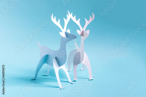 Origami paper deer in blue and white on a bright blue background.