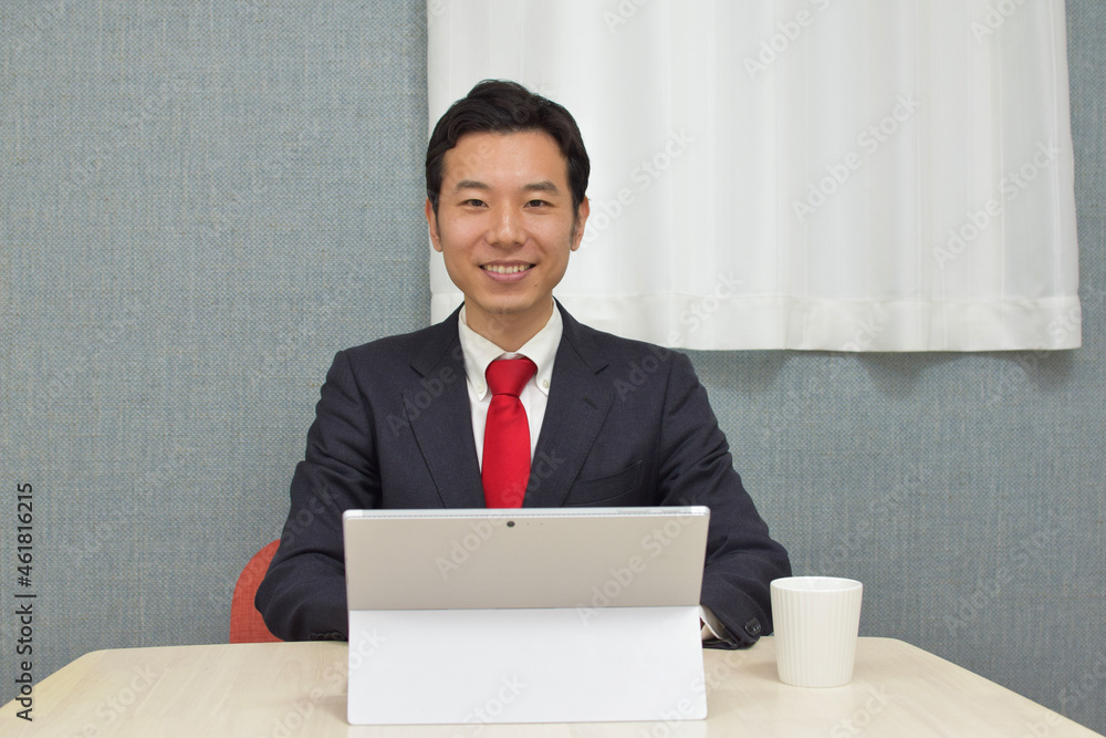 A young Asian man wearing business suit works on a pc and do telework at home A young Asian man wearing business suit works on a pc and do telework at home