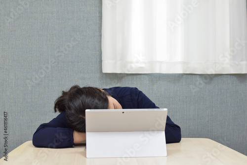 A young Asian woman gets tired and starts sleeping on the desk during telework