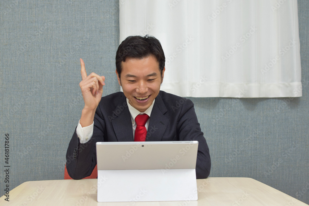 A young Asian man wearing business suit gets convinced in front of a pc during telework at home A young Asian man wearing business suit gets convinced in front of a pc during telework at home
