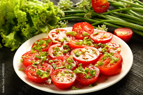 Plate of delicious homemade organic tomato salad. with fresh herbs and greens.
