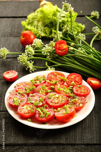 Delicious and healthy organic tomato salad with fresh herbs and green leaves.