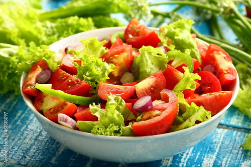 Homemade organic tomato green vegetable salad served in white ceramic bowl. diet meal.