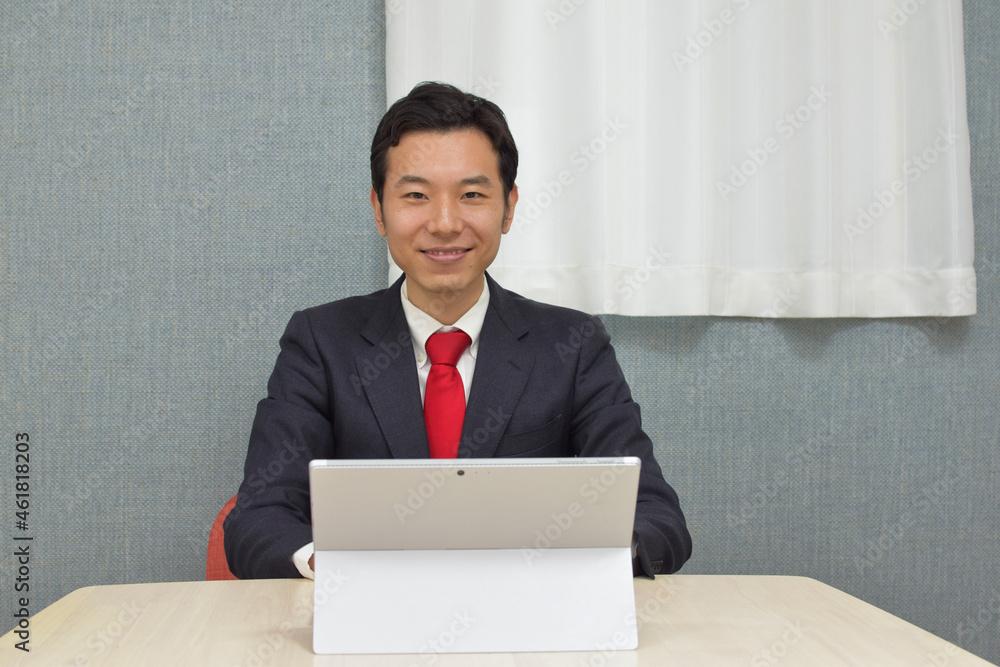 A young Asian man wearing business suit during telework at home works on a pc and types words A young Asian man wearing business suit during telework at home works on a pc and types words
