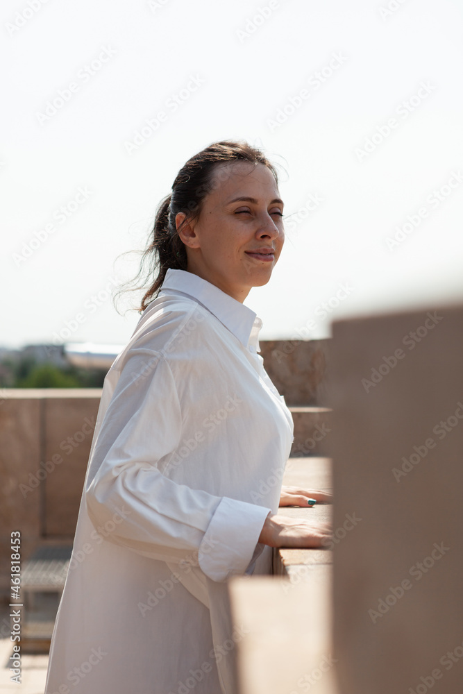 Happy caucasian female standing on tower rooftop enjoying seeing panoramic view of metropolitan city during summer vacantion. Landscape view of urban buildings from observation point. Travel concept Happy caucasian female standing on tower rooftop enjoying seeing panoramic view of metropolitan city during summer vacantion. Landscape view of urban buildings from observation point. Travel concept