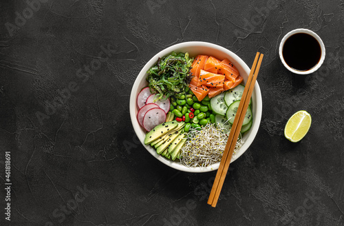 Keto diet poke bowl with salmon, avocado, and edamame beans. over dark background. top view, copy space. photo