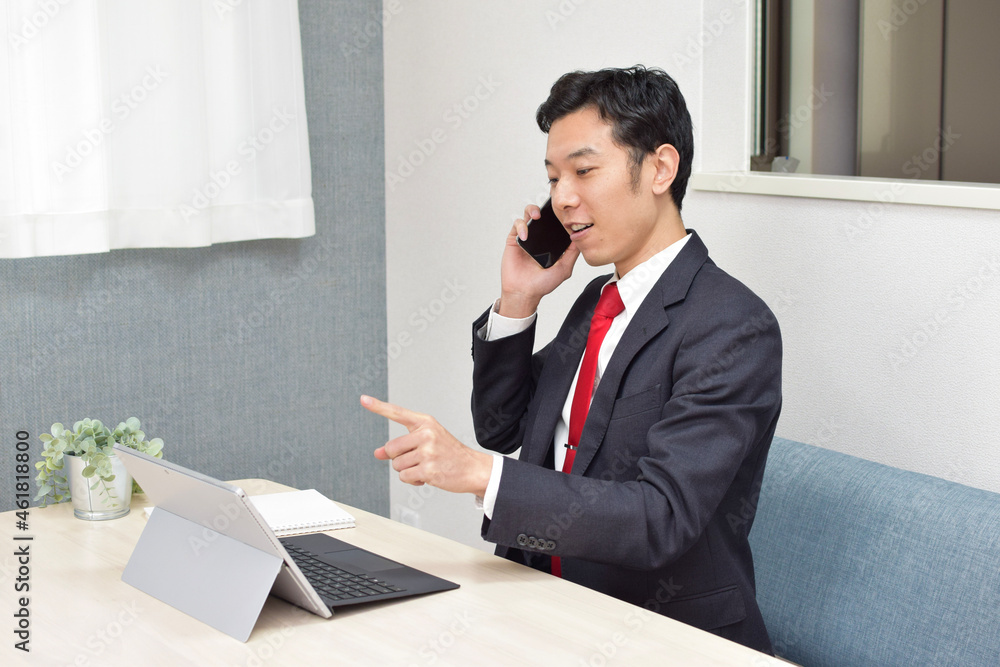 A young Asian man gets convinced while talking on his phone during telework at home A young Asian man gets convinced while talking on his phone during telework at home