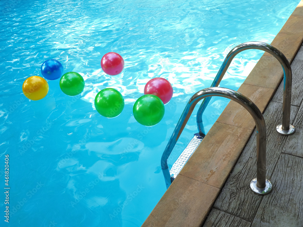 Pool fun concept with an inflatable plastic beach ball floating in cool ...