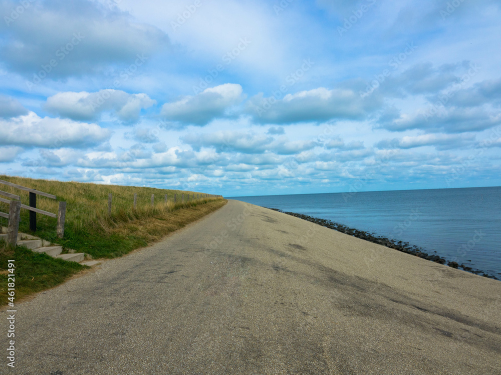 Shoreline of Texel Island, with view over the wadden sea, with cumulus clouds  and a bike lane over a dike. Texel Island, Netherlands