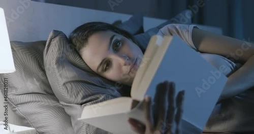 Woman relaxing in bed and reading a book photo