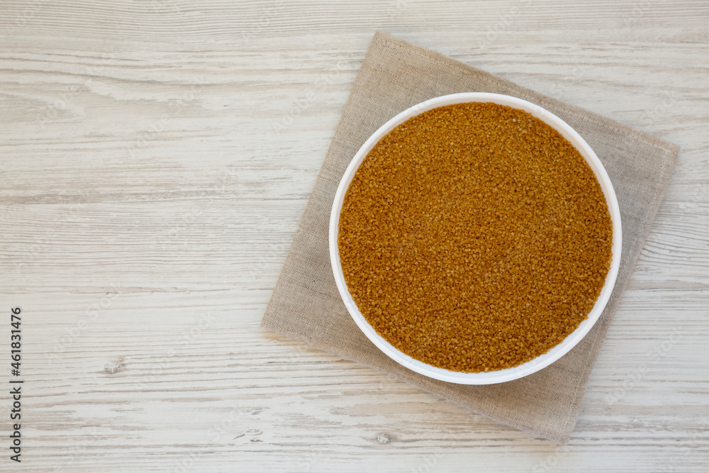 Organic Brown Sugar in a White Bowl on a white wooden surface, top view. Flat lay, overhead, from above. Space for text. Organic Brown Sugar in a White Bowl on a white wooden surface, top view. Flat lay, overhead, from above. Space for text.