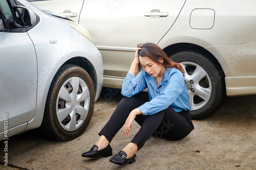 Asian woman sitting stressed Had an accident driving a car into the side of another car Because the road is slippery, it rains. Insurance concept, drive carefully in Thailand rainy season © SUPERMAO