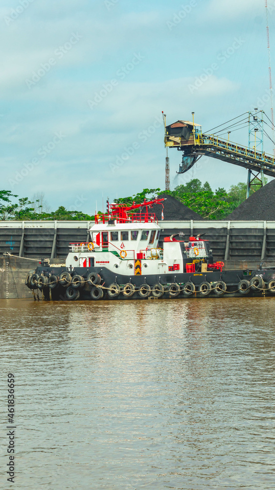 Fototapeta premium Barge full of black coal cruising on Mahakam River, Borneo, Indonesia. Mining and energy