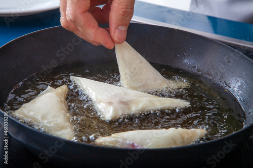 Manos  de cocinero friendo pestiños en aceite caliente. Cook's hands frying pestiños in hot oil photo