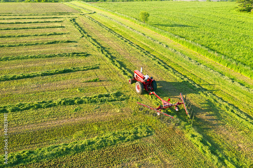 Aerial view of a red tractor is working on the grass field