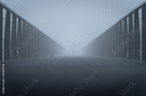 Cyclist on an wooden bicycle lane on a morning with dense fog.