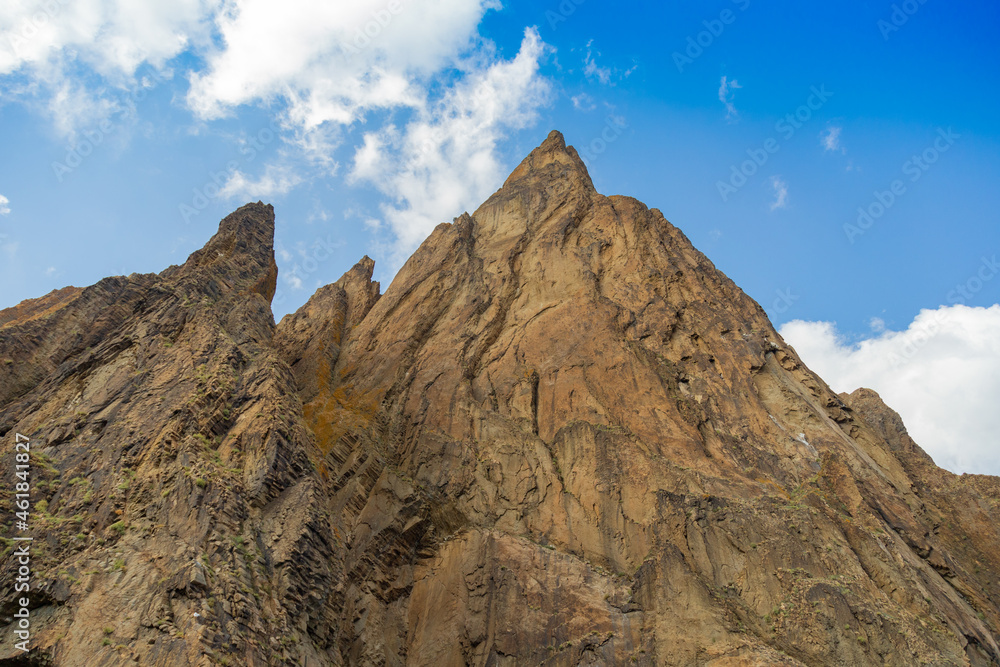 Pointed brown and yellow mountains with very sharp descents and expressive texture against the background of deep blue sky