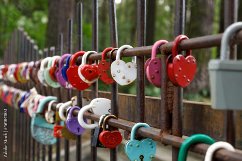 Heart-shaped padlocks hanging on a fence. Selective focus.