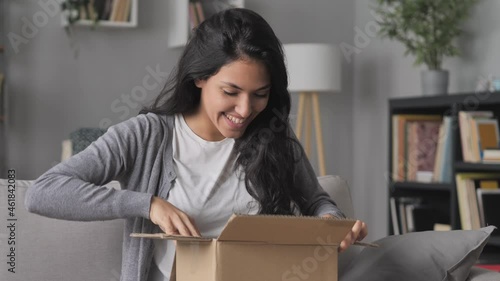 happy woman sits on the couch open online order cardboard box,satisfied female customer opening,unboxing postal parcel package,home shipping delivery concept photo