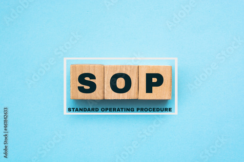 SOP - acronym from wooden blocks with letters, abbreviation SOP standard operating procedure concept, light blue background