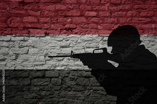 Soldier silhouette on the old brick wall with flag of yemen country.