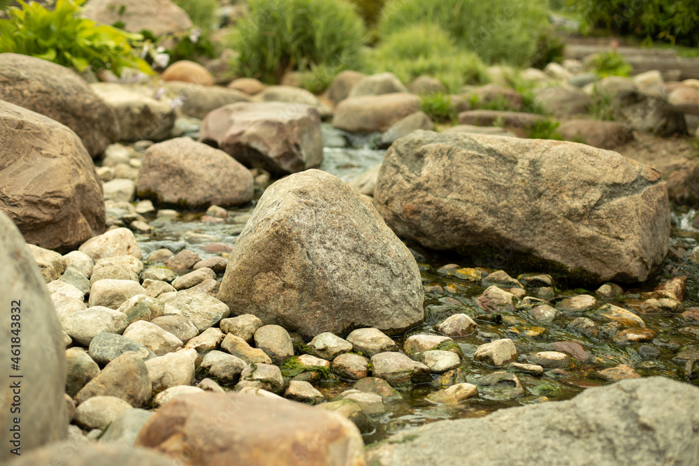 Stones in the landscape design of the park. Cobblestones in a mountain stream. Artificial pond with a waterfall. Stones in the landscape design of the park. Cobblestones in a mountain stream. Artificial pond with a waterfall.