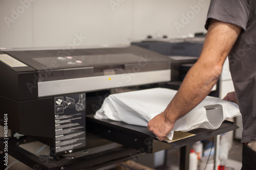 Graphic print technician work on digital t-shirt printing machine printer