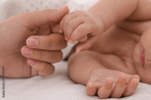 Mother with her cute baby on bed, closeup of hands © New Africa