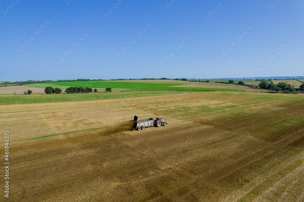 The tractor scatters manure on the field. Feeding the soil before harrowing. View from above. The tractor scatters manure on the field. Feeding the soil before harrowing. View from above.