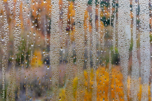 Natural drops of water on the window glass. Misted glass in fall, autumn background.