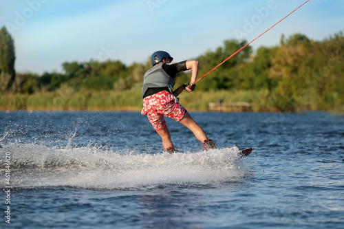 Teenage boy wakeboarding on river, back view. Extreme water sport © New Africa