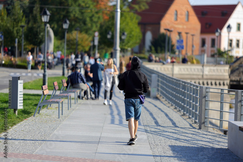 Młody mężczyzna idzie chodnikiem wzdłuż kanału we Wrocławiu.