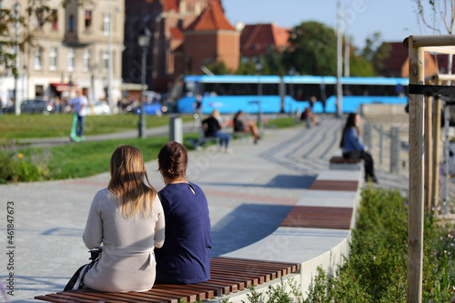 Dwie kobiety siedzą na ławkach nad rzeką Odrą we Wrocławiu.