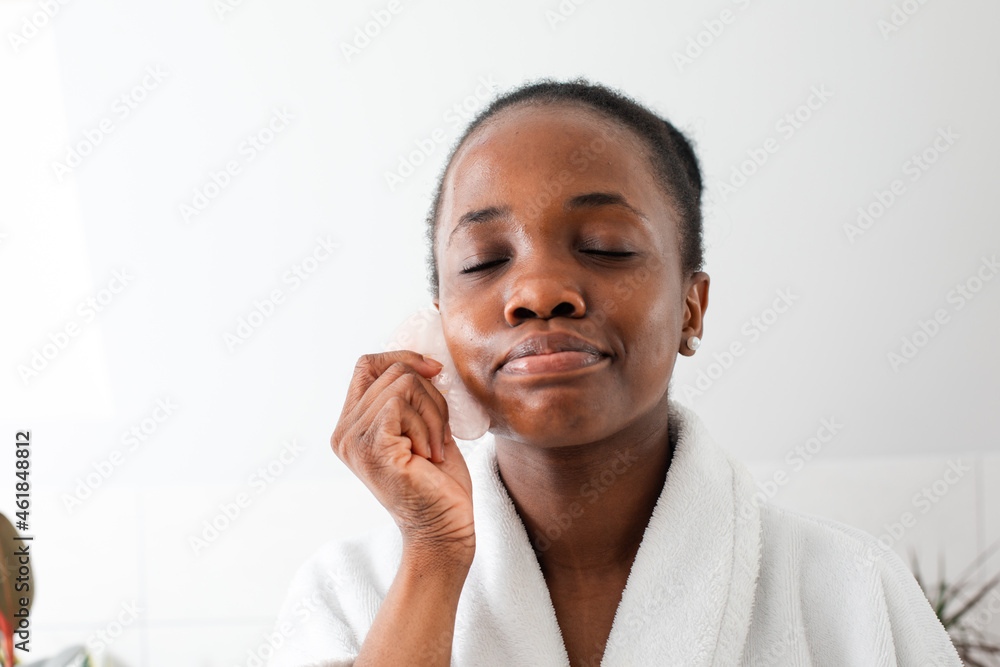 Lovely african girl massaging face with rose quartz gua sha Lovely african girl massaging face with rose quartz gua sha