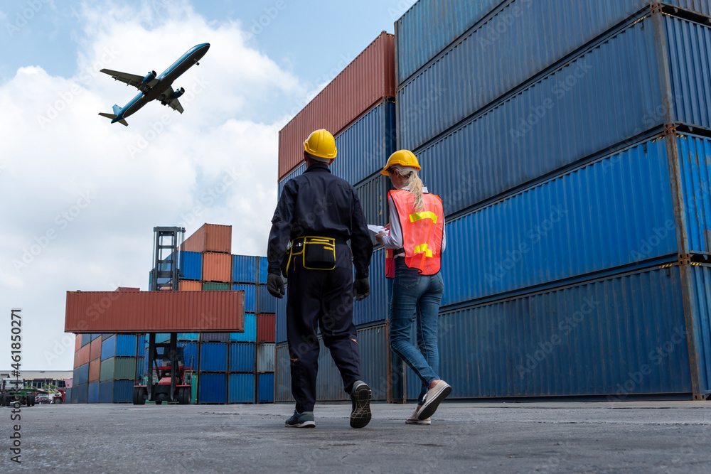 Industrial worker works with co-worker at overseas shipping container port . Logistics supply chain management and international goods export concept . - obrazy, fototapety, plakaty 