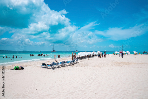 Fototapeta Naklejka Na Ścianę i Meble -  Cancun, Mexico. May 30, 2021. Deckchairs under canopy shade for resting on beach sand in front of sea with yachts. Tourists enjoying beach summer holiday