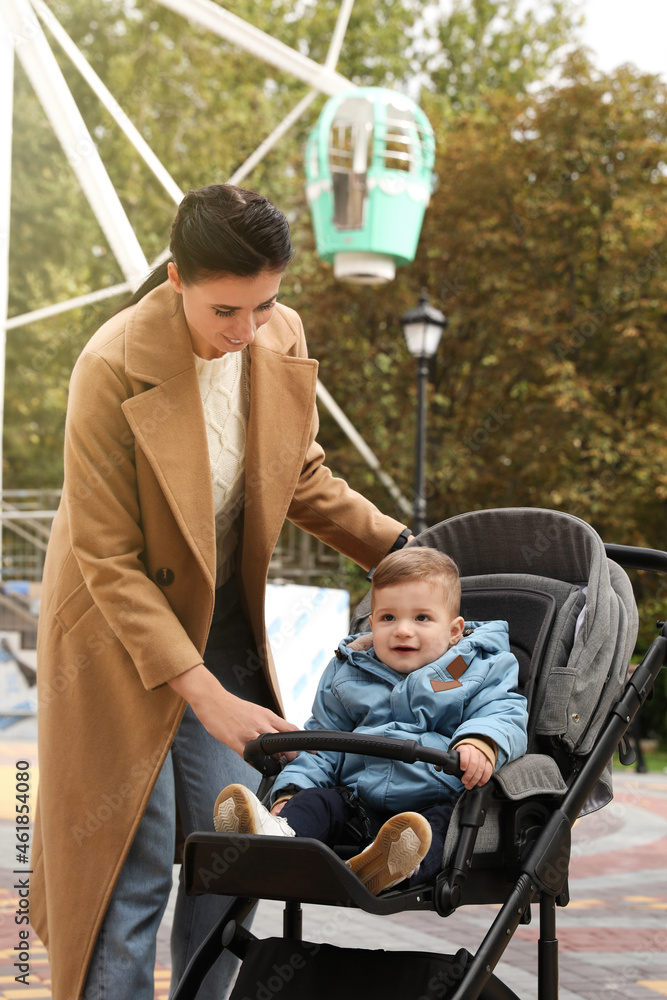 Happy mother walking with her son in stroller outdoors Happy mother walking with her son in stroller outdoors