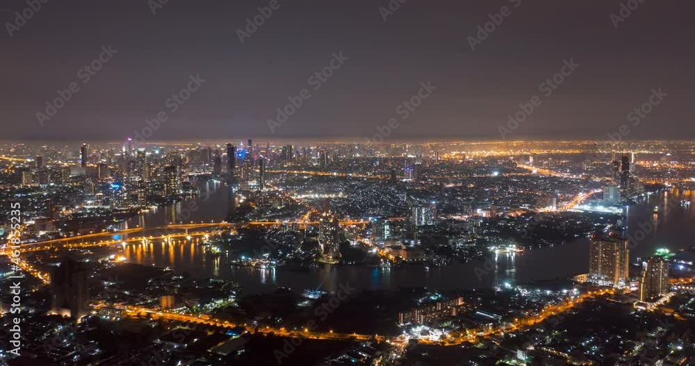 Aerial view night time lapse of landmark financial district and business center with skyscraper over Chao Phraya River at Bangkok, Thailand. Amazing drone footage over smart urban city skyline in 4K. Aerial view night time lapse of landmark financial district and business center with skyscraper over Chao Phraya River at Bangkok, Thailand. Amazing drone footage over smart urban city skyline in 4K.