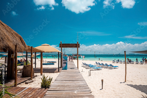 Cancun  Mexico. May 30  2021. Wooden pier leading from sand into sea with moored yachts or sailboat on water surface. Tourists holidaying at beach