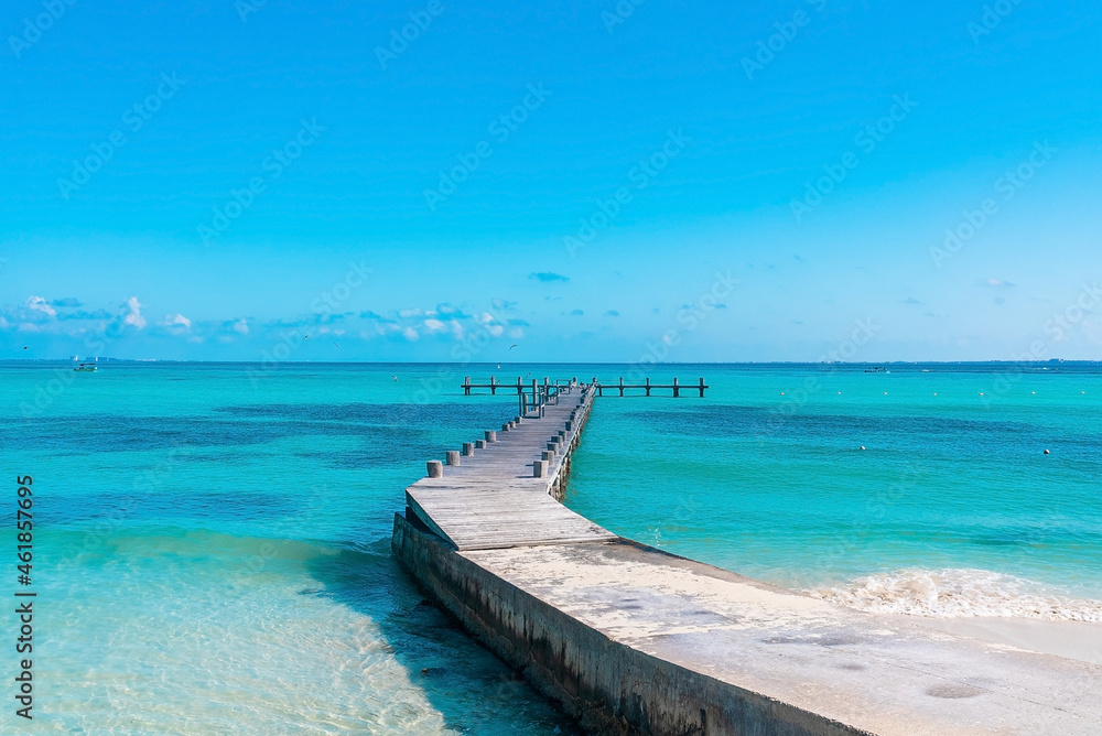 Flock of seagull birds flying over empty wooden jetty on blue tranquil sea water surface against sky Flock of seagull birds flying over empty wooden jetty on blue tranquil sea water surface against sky