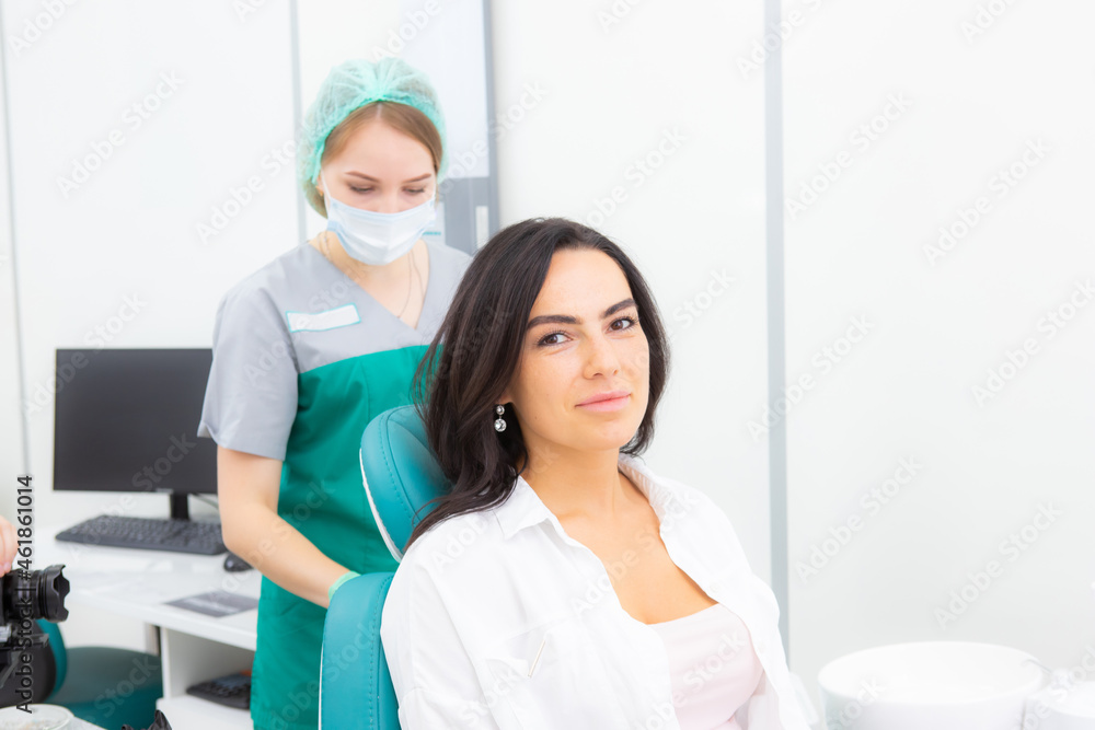 The dentist's assistant puts the protection on the patient, the napkin on the chest The dentist's assistant puts the protection on the patient, the napkin on the chest