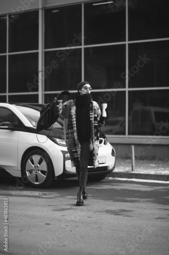 Woman drinking coffee and charging electro car