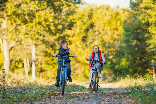 happy kids ride a bike in the autumn forest