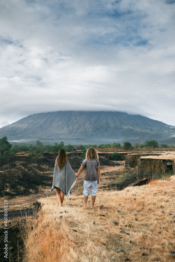 Man and woman in stylish clothes, look at the mountains and hold hands, autumn, back view. Man and woman in stylish clothes, look at the mountains and hold hands, autumn, back view.